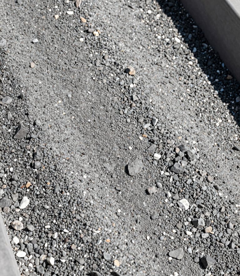 Close-up of a vibrating screen sorting gravel by size, sharp high-contrast rock textures, bright sunlight, industrial photography