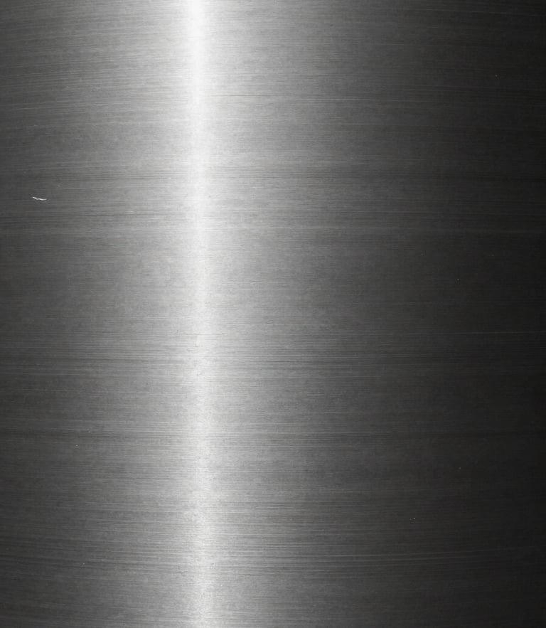 Extreme close-up of brushed steel texture with sharp linear reflections, high-contrast museum lighting, monochrome, 35mm