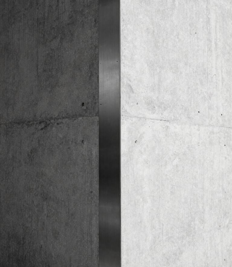 Minimalist architectural detail of a concrete corner meeting brushed steel under hard, high-contrast sunlight, sharp shadows, monochrome, 35mm