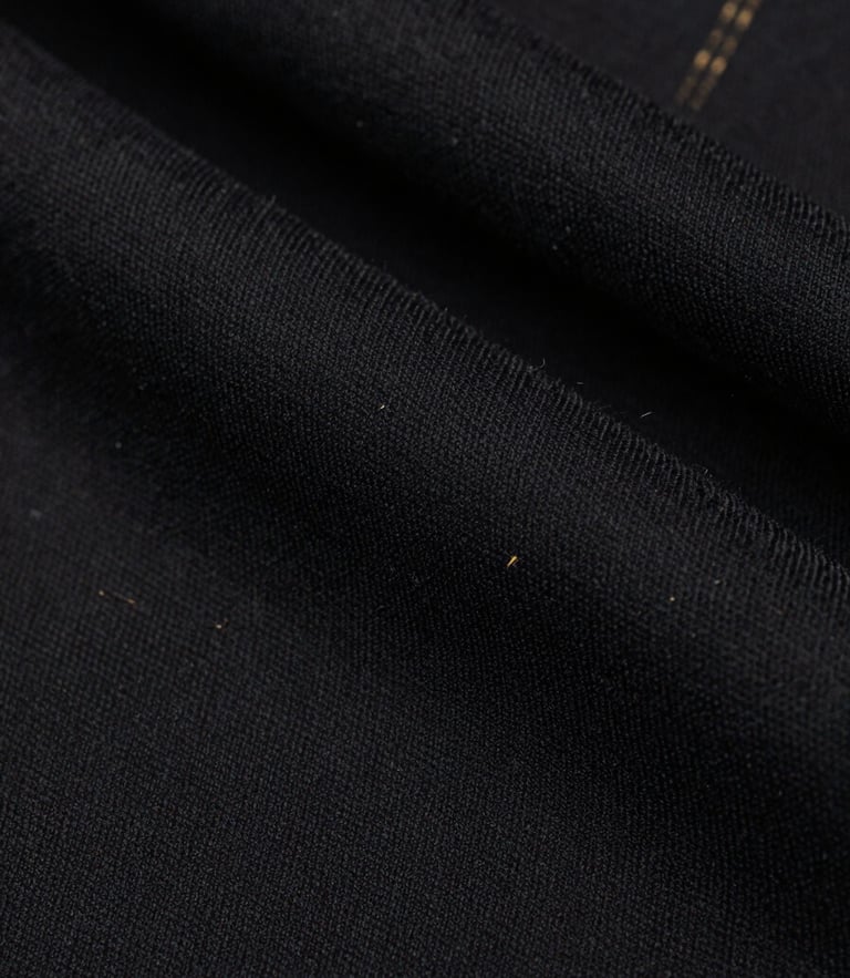 Macro close-up of heavy-drape black cotton fabric texture, showing precise embossed detailing and raw textile fibers, high-contrast studio lighting, desaturated tones