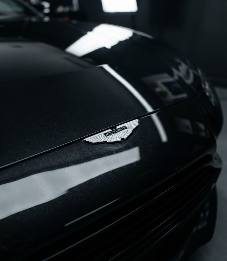 Sleek automotive photography of a sports car hood with sharp reflections under studio lighting, deep metallic black tones, macro lens detail, 35mm