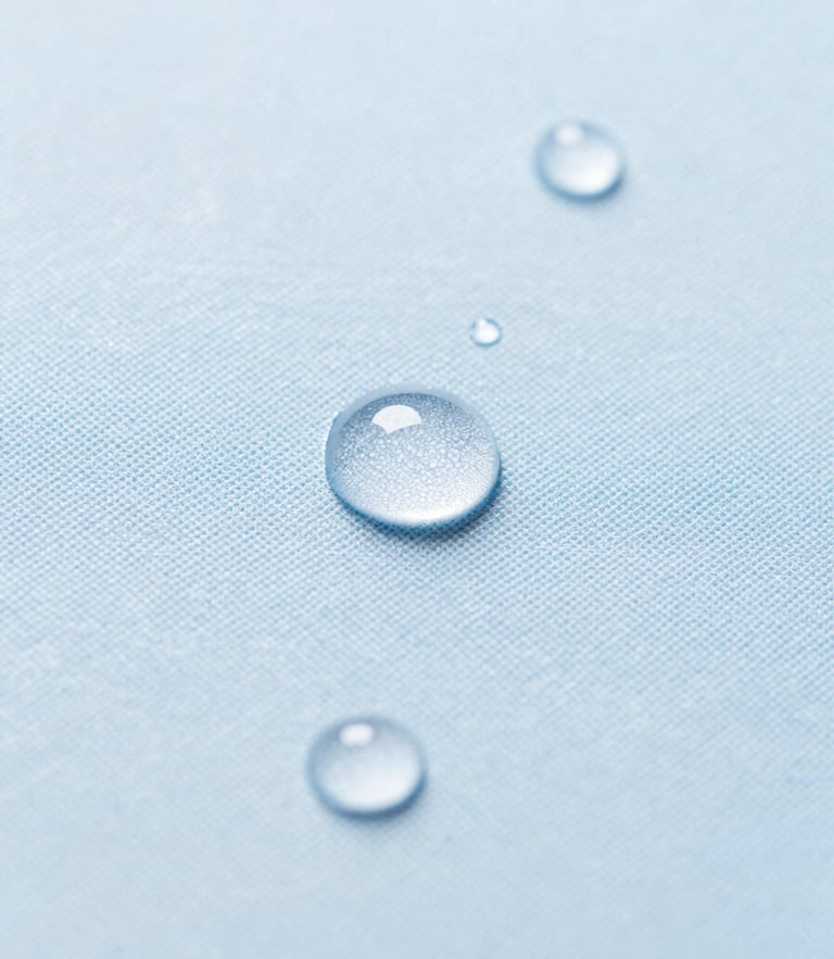 Macro photograph of water droplets perfectly beading on a clean slate blue fabric texture, bright natural daylight, 35mm lens