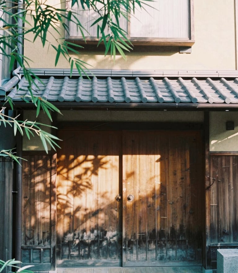 A serene morning view of a traditional wooden machiya townhouse entrance in Kyoto, soft sunlight filtering through bamboo leaves, 35mm film look