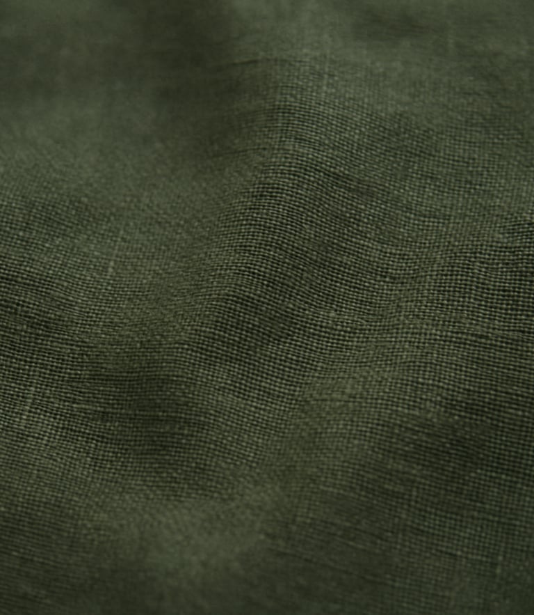 Macro detail shot of heavy forest green linen fabric texture, soft overcast daylight, 35mm film grain