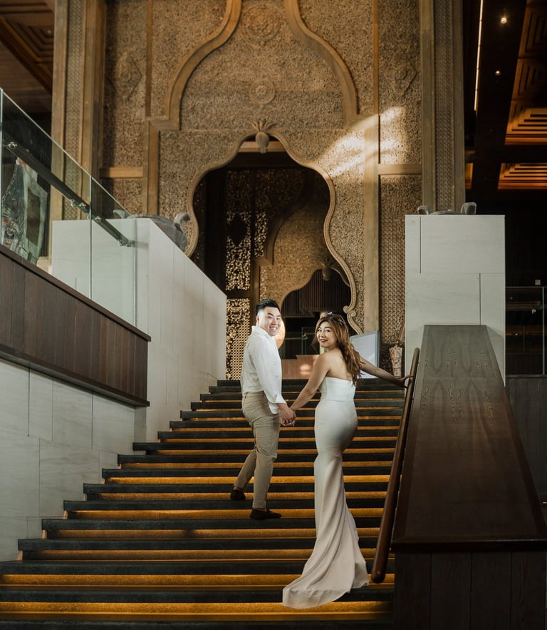 Couple walking down the grand staircase during a luxury prewedding photoshoot at Apurva Kempinski Bali