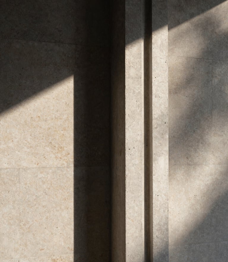 A vertical medium format photograph of a modern concrete column meeting a travertine wall, dramatic sunlight casting sharp geometric shadows, architectural detail