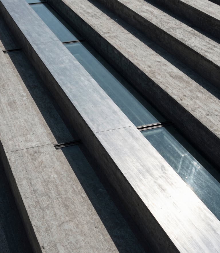 High-angle architectural perspective of concrete and glass lines, cool-toned lighting with sharp silver reflections and deep shadows, structural integrity.