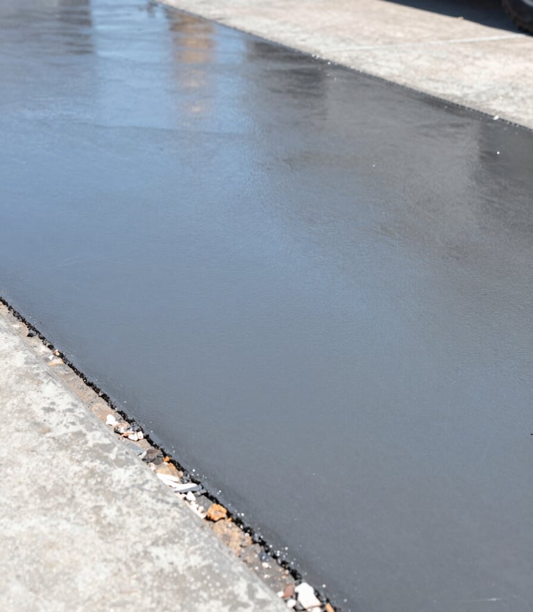Low-angle sharp industrial photograph of a newly poured concrete driveway reflecting bright Texas sunlight, crisp steel-blue tones, 35mm lens
