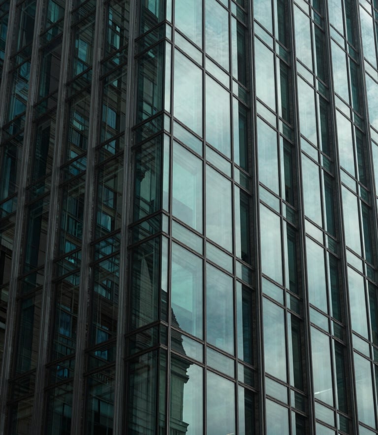Low-key architectural photograph of a modern glass high-rise facade reflecting cool neon-mint light patterns, sharp geometric shadows, high-contrast composition