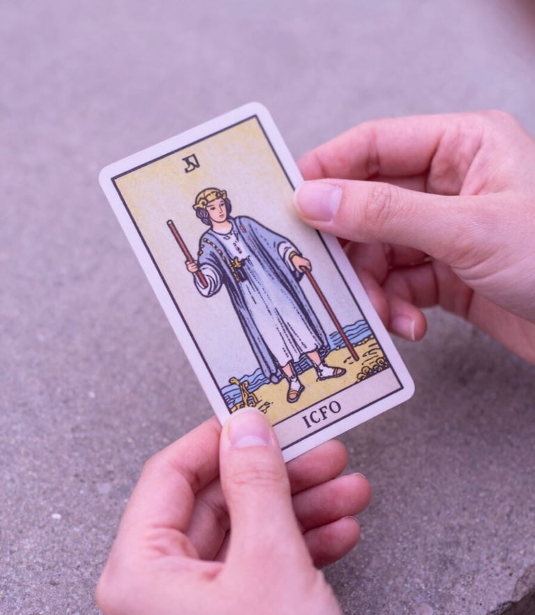 Soft-focus hands with clean manicures holding a single tarot card over a stone surface, luminous morning light, dusty pink tones, 35mm