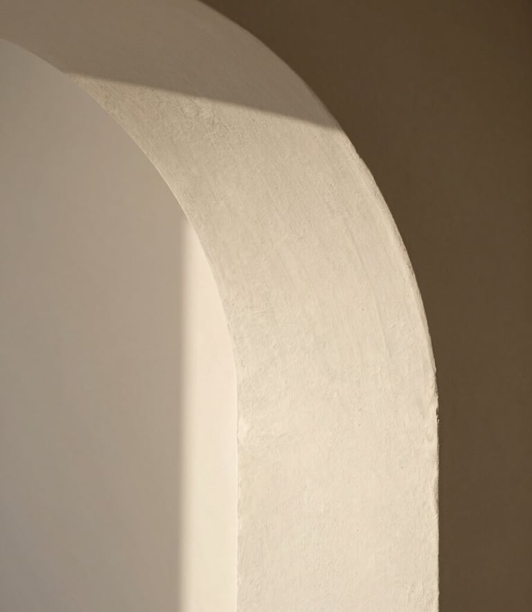 Close-up of soft morning light casting a curved shadow on a textured plaster wall, minimalist architectural detail, warm neutral tones, shallow depth of field