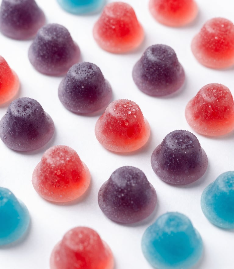 Macro close-up of natural pectin gummy texture resting on a clean cream stone tile, soft studio lighting, muted purple shadows, elegant depth of field