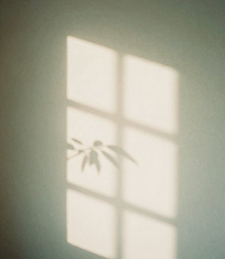 Soft diffused window light casting gentle shadows of leaves on a warm off-white wall, calming sage green tones, minimal and serene atmosphere, 35mm photography