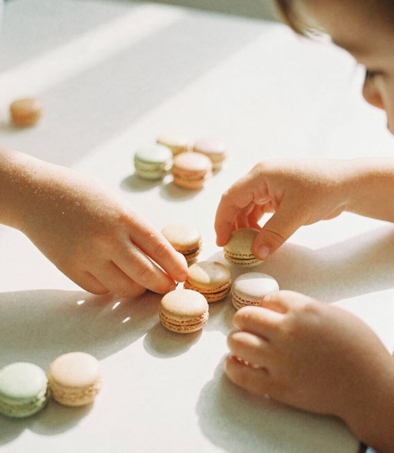 Warm editorial photography of a young child's hands sorting smooth wooden Montessori beads on a sunlit table, soft morning daylight, gentle macaron pastel tones, shallow depth of field, candid, 35mm film style