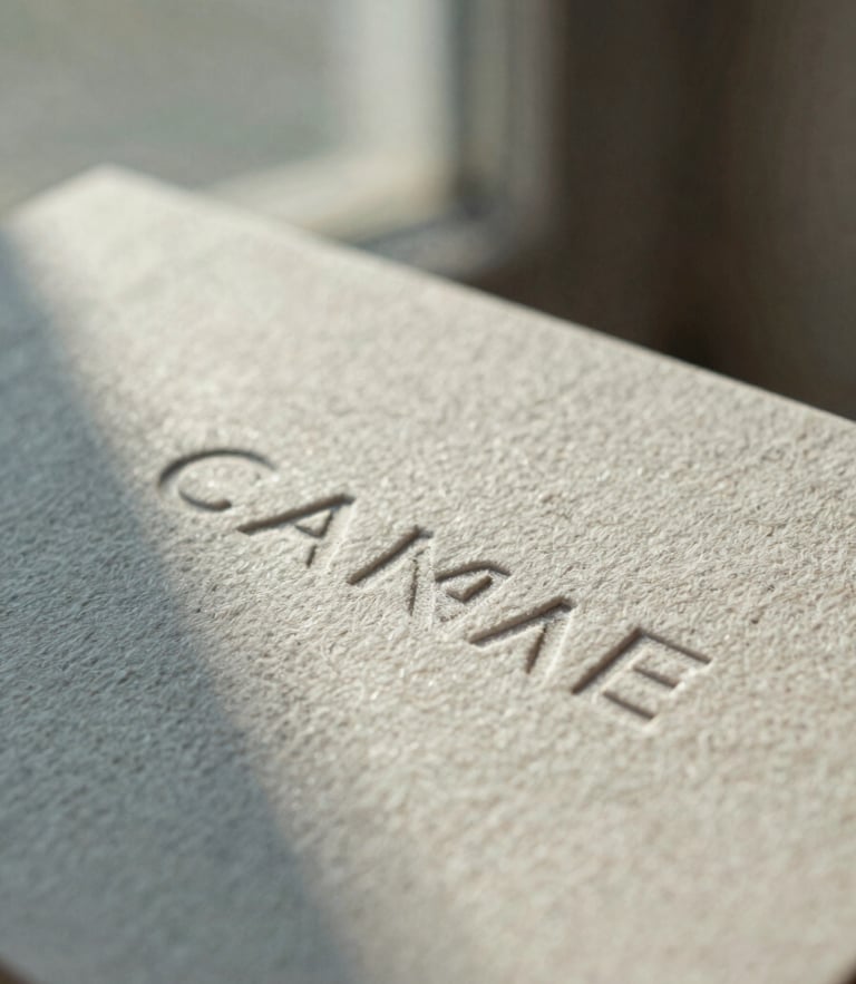 Macro close-up of tactile linen paper business cards with embossed typography, soft diffused north-facing window light, muted dusty blue shadows, editorial 35mm film texture.