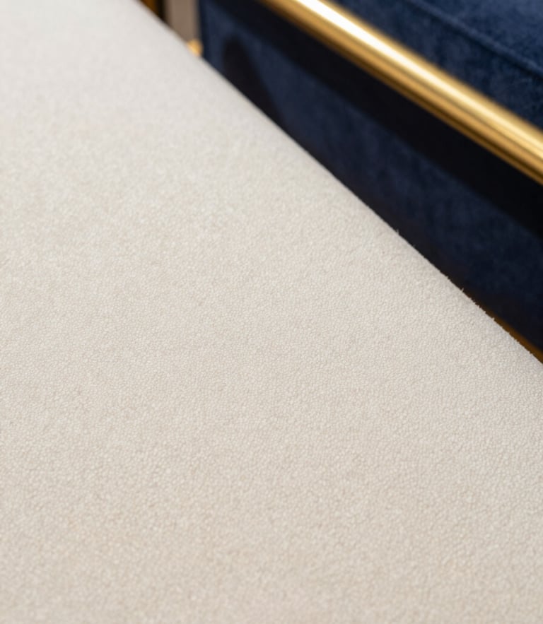 Macro photograph of pristine, clean cream bouclé fabric texture, soft architectural light, gold accent details, sharp focus