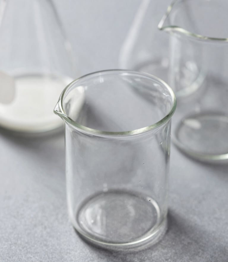 Macro photograph of clean laboratory glassware under bright daylight, soft shadows, slate-gray background, shallow depth of field.