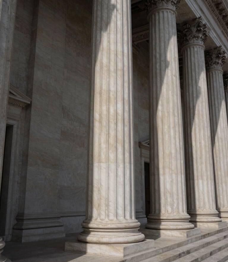Wide angle photograph of neoclassical courthouse columns, dramatic side-lighting casting deep shadows, crisp alabaster stone texture.