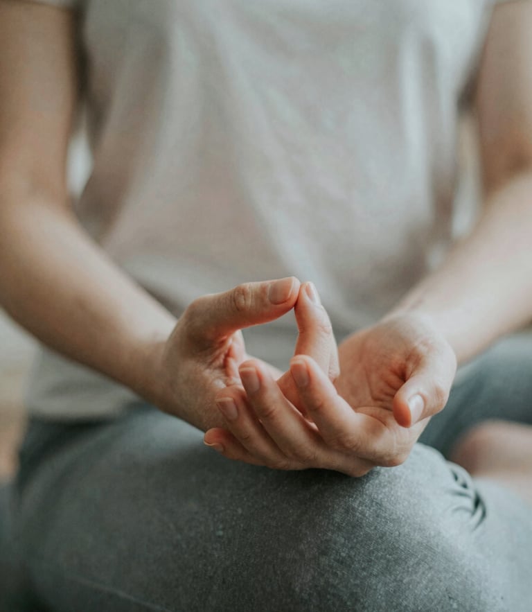 A close-up of hands in a meditative pose, soft backlit ambient light, muted pearlescent and obsidian tones, shallow depth of field, 35mm