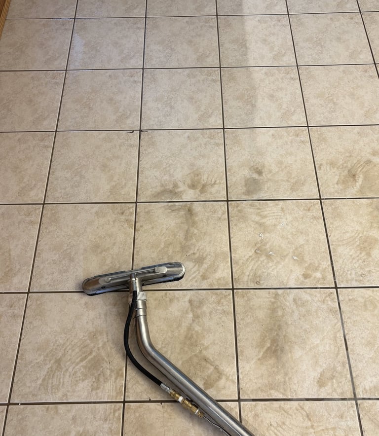 Tile and grout cleaning using a high-pressure wand showing clear before and after floor results.