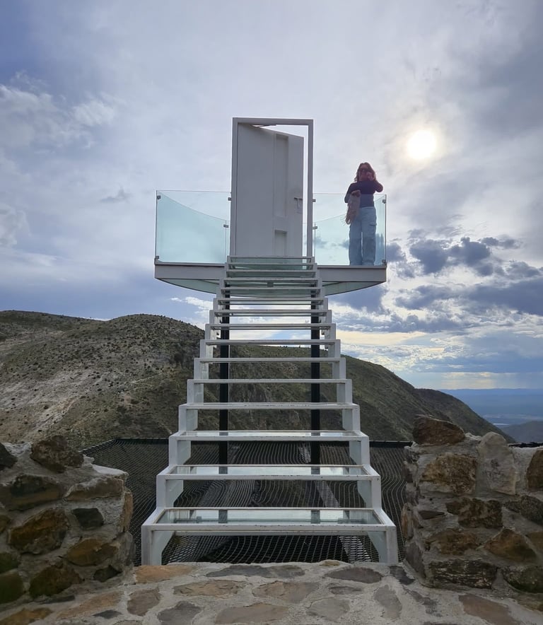 Mujer se encuentra de pie en plataforma de observación, en lo alto de una escaleras que van al cielo