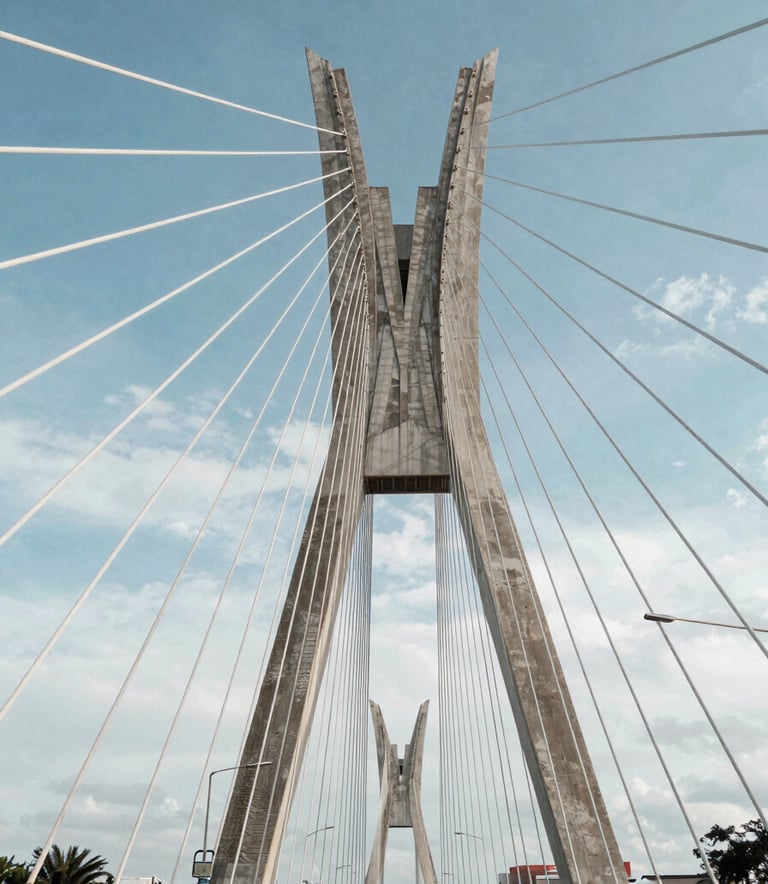 A high-end architectural shot of a modern bridge or infrastructure project in a South American urban setting. The composition uses leading lines to convey precision and engineering strength. Soft daylight, clean Prussian Blue and Powder Blue tones in the sky and materials.