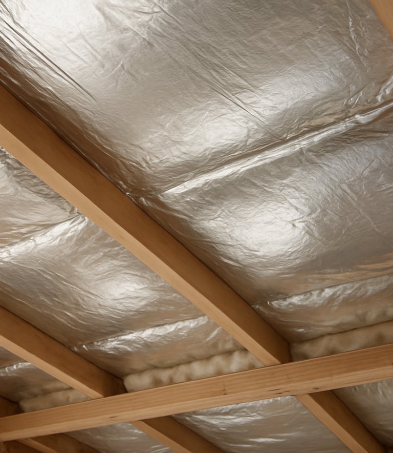 Close-up of neatly installed silver foil sarking and insulation in an Australian home ceiling cavity. Soft daylight highlights the precision and expert craftsmanship of the installation in a clean, professional finish.