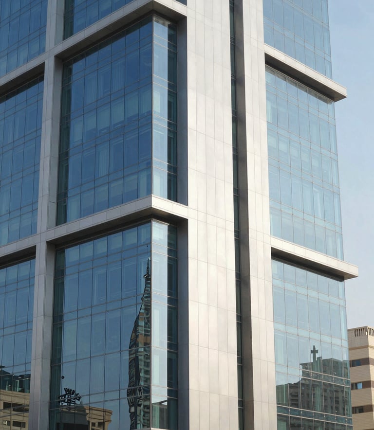 Professional photography of a modern commercial building in Riyadh with a sleek glass and aluminum facade. Middle Eastern / Gulf architectural context. Bright daylight reflecting off the clean, blue-tinted glass panels, emphasizing professional craftsmanship and modern urban design.