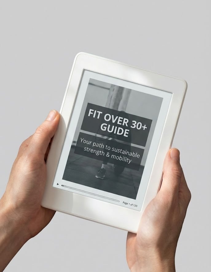 Hands holding a white tablet displaying a Fit Over 30 fitness guide for strength and mobility.