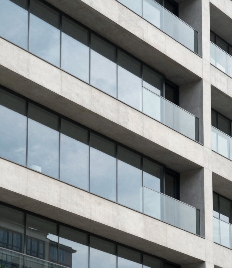 A close-up architectural detail of a modern building facade featuring clean geometric lines, glass panels, and smooth concrete surfaces. The lighting is bright and airy, reflecting a Cloud White and Muted Slate Grey color scheme. The composition is sharp and minimalist, emphasizing structural precision.