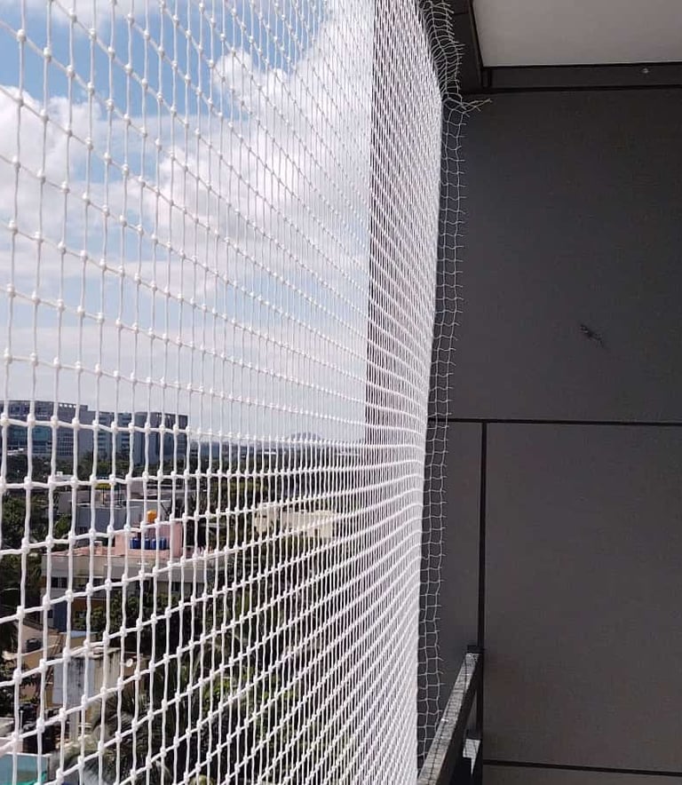 A clean, modern balcony with a professionally installed pigeon safety net. The lighting is soft and 