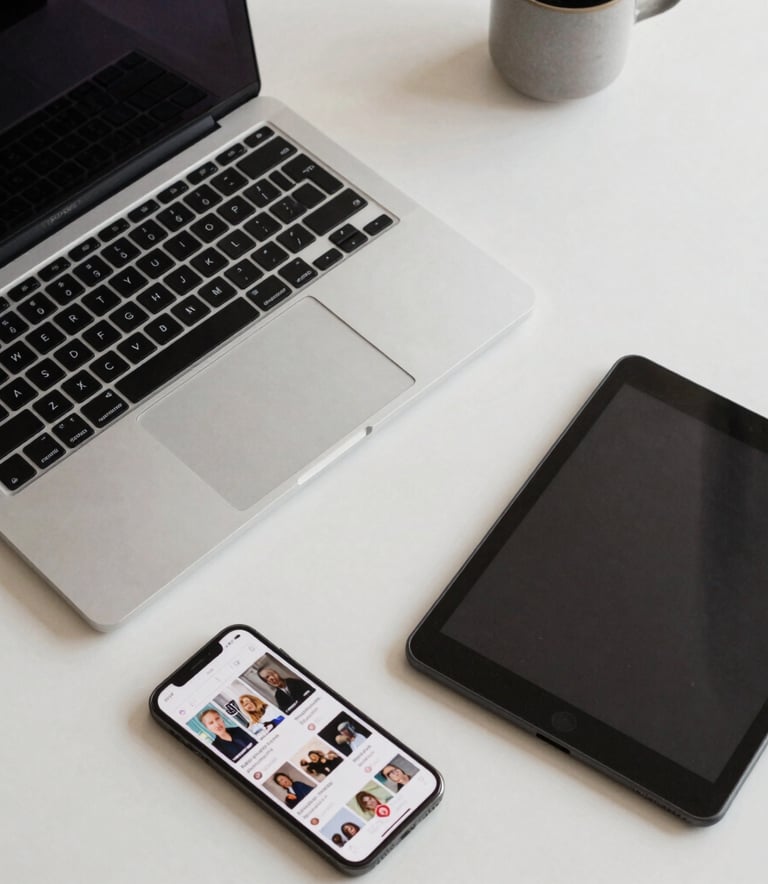A top-down view of a modern desk with a high-end laptop, a smartphone displaying a social media feed, and a professional designer's tablet on a clean thistle-colored surface in a bright North American office.