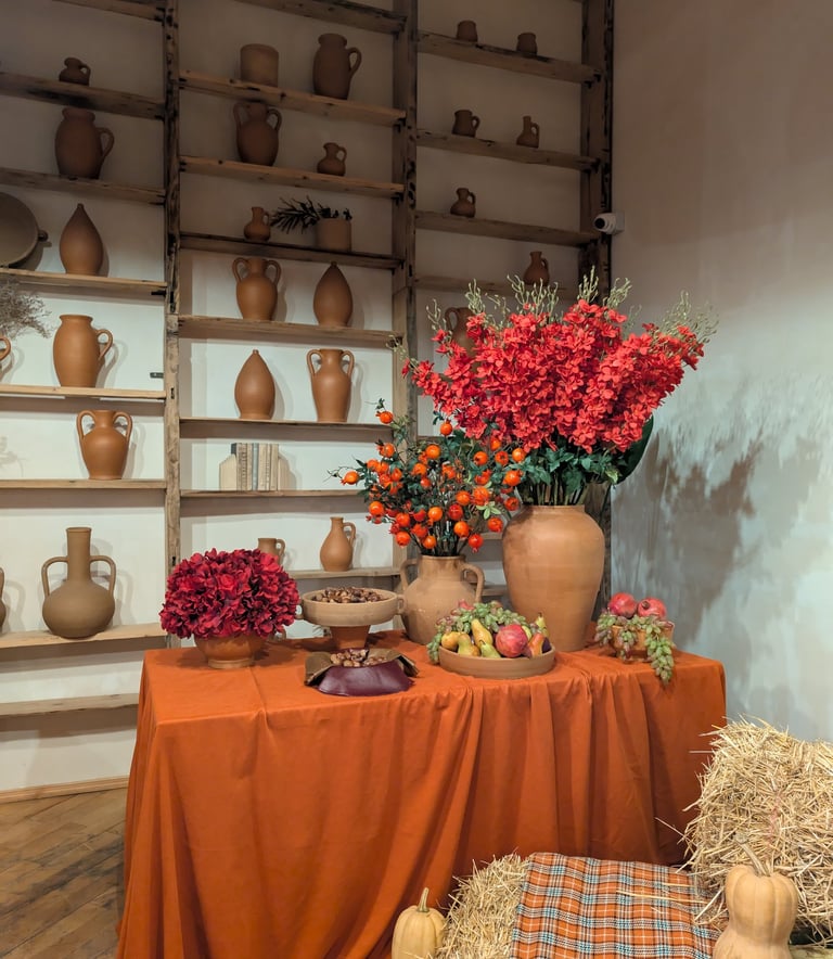 A wall with clay pots and a table with clay pots and flowers at Gala in Kutaisi Georgia
