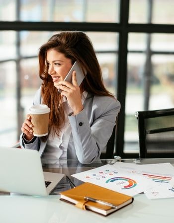 happy realtor working at desk and talking to client on phone