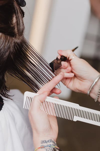 a woman is getting her hair cut by a hairdressucker