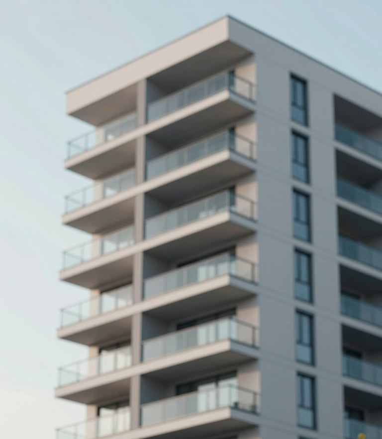 A modern apartment building facade with clean lines and glass balconies under a clear sky, edited with a professional, slightly desaturated look using the palette tones #4C6A7F and #F8F8F4.