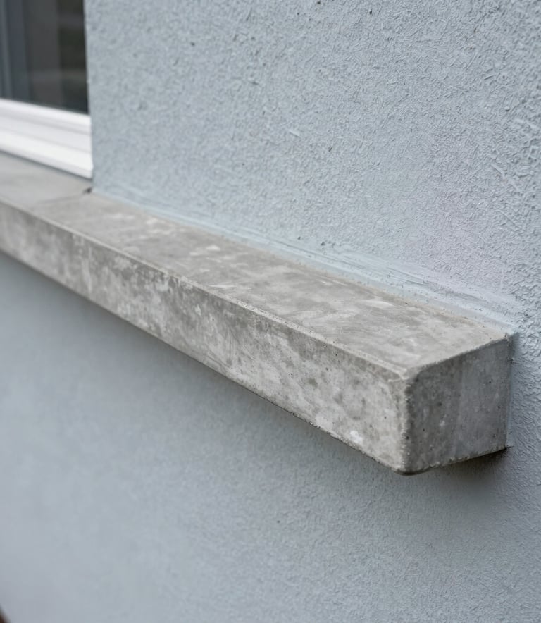 A high-quality finished cement window sill on a stucco house in North American / Florida, showing a smooth dusty gray surface and perfect edges against a light blue-gray wall.