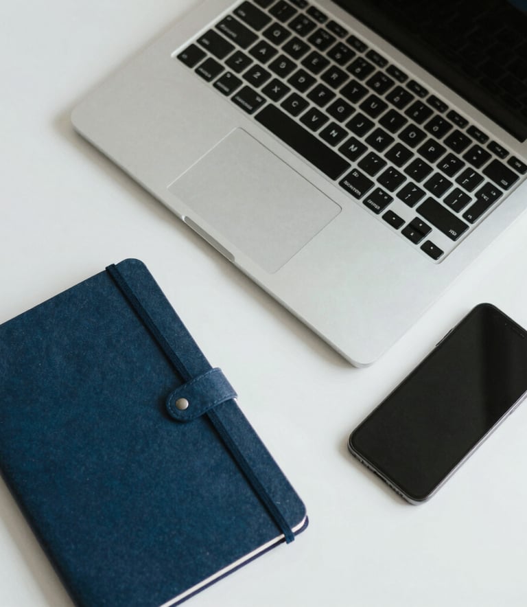 A top-down view of a clean desk with a high-end laptop, notebook, and smartphone, soft natural lighting, professional minimalist aesthetic, light gray and blue tones.