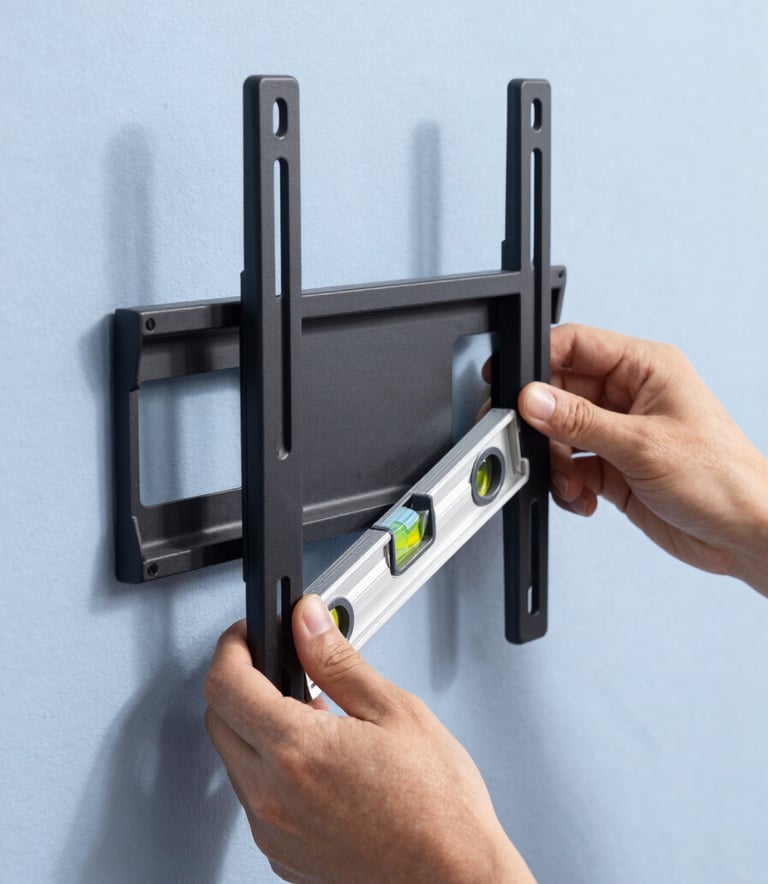 Close-up of a high-quality TV wall mount bracket being installed on a Pale Lavender Blue wall, a person's hands using a level tool, bright natural North American sunlight, professional photography.