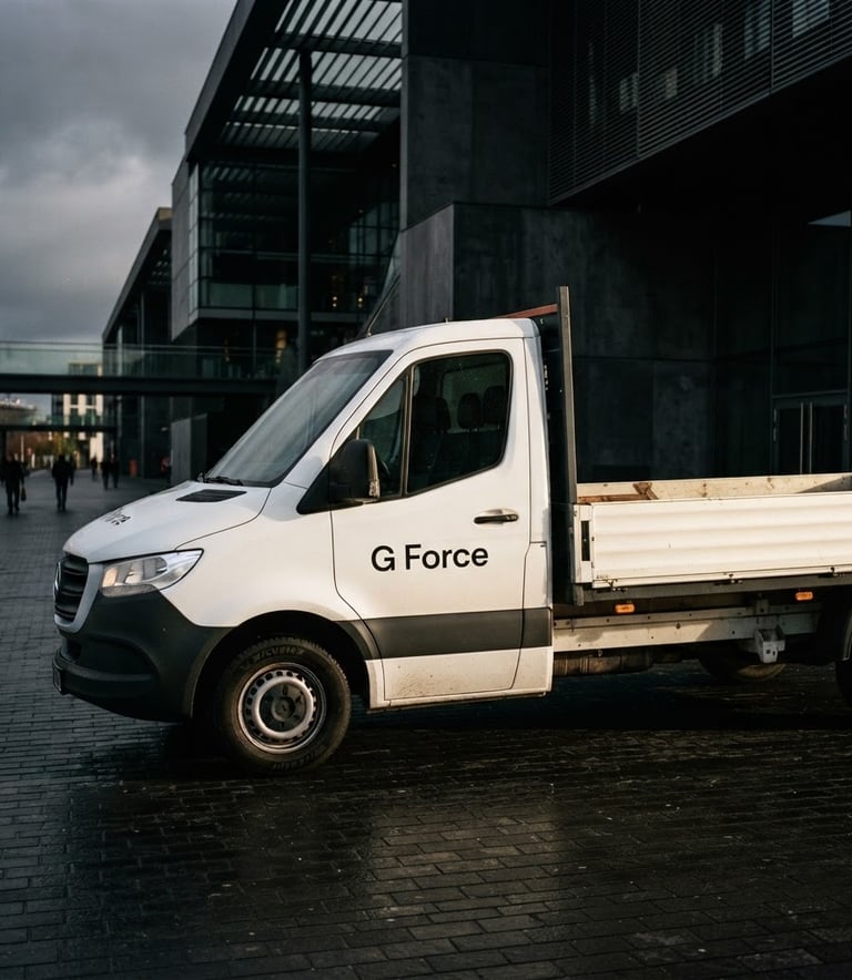 A clean white drop-side delivery van with minimalist black 'G Force' branding parked outside a modern architectural building, moody editorial photography, high-contrast side lighting, 35mm.