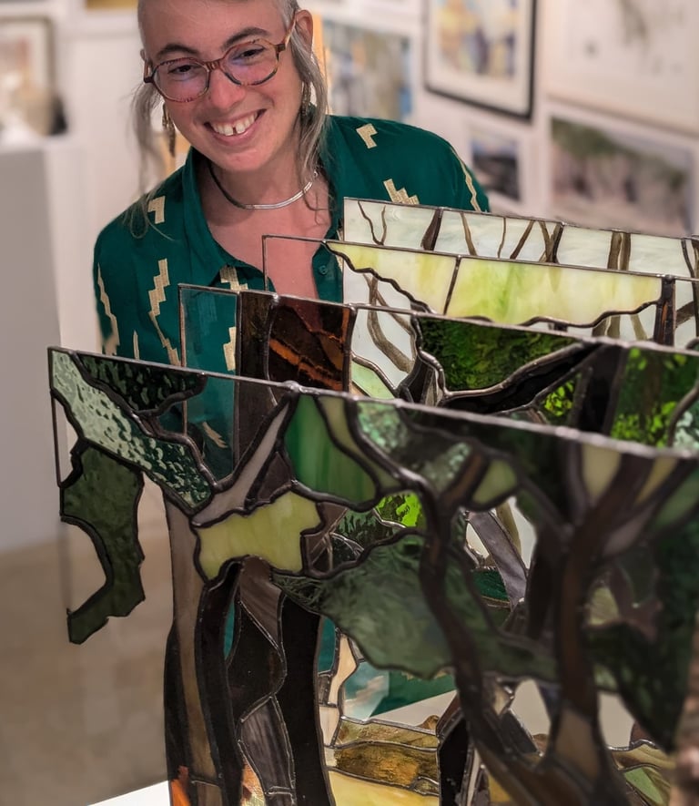 Image of Artist Laura Kriefman at Biennale Exhibition opening. Laura is smiling and looking at  her bespoke glass art