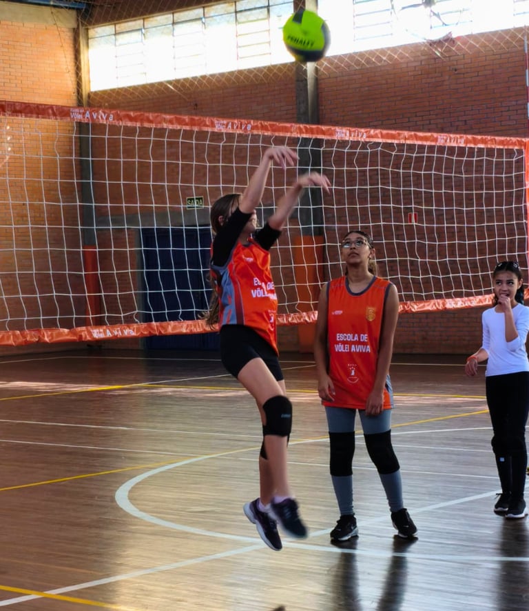 Aluna da escolinha de vôlei treinando saque durante aula no Centro Poliesportivo Aviva, em Caxias do