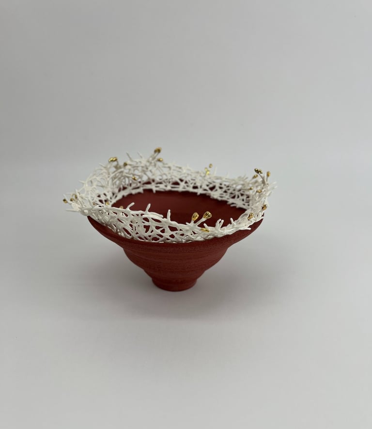 A thrown stoneware ceramic tiered bowl, topped with a porcelain white crown sculpture, tipped gold