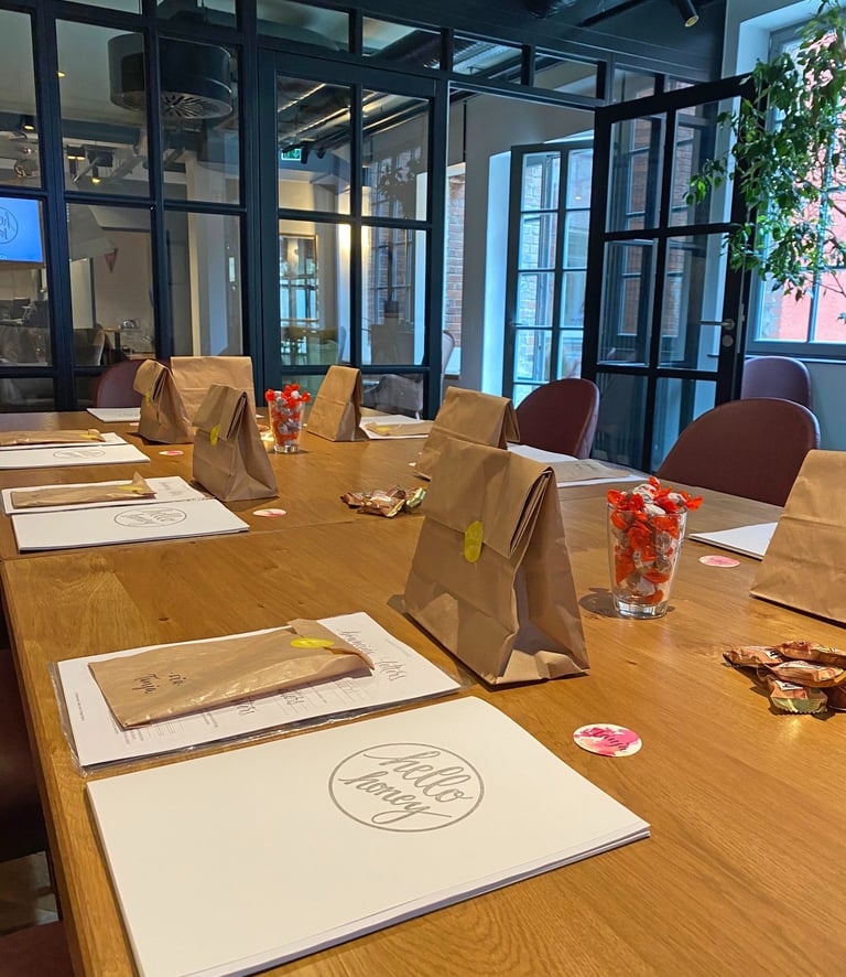 Brown paper gift bags and event programs on a wooden conference table in a modern office meeting room.