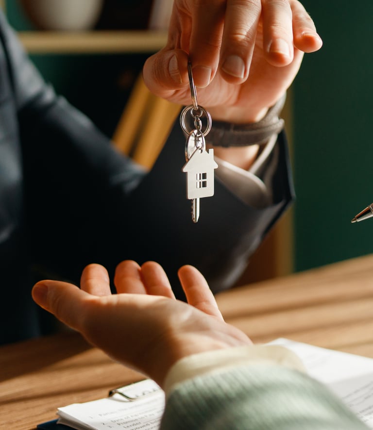Real estate agent handing house keys to a new homeowner after signing a mortgage contract.