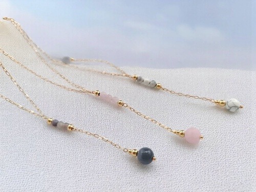 Ensemble de 3 colliers en plaqué or et pierre naturelles, sur du sable 