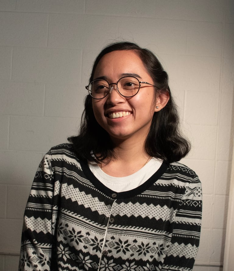 Portrait of Fatima Fabillar, smiling and wearing a patterned cardigan against a neutral background