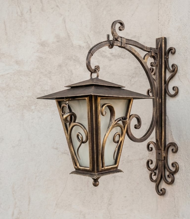 Vintage bronze outdoor wall lantern with ornate scrollwork on a textured stone wall.
