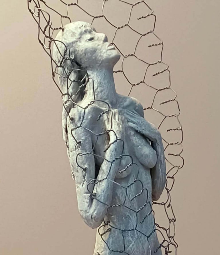 Close up of a female figure, leaning back with eyes closed, surrounded by a wire netting enclosure