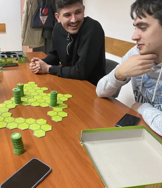 Grupa ljudi igra društvenu igru Battle Sheep, uživajući u strateškoj zabavi na stolu